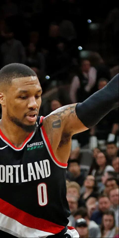 Patty Mills #8 of the San Antonio Spurs falls to the ground as Damian Lillard #0 of the Portland Trail Blazers stand over him at AT&T Center on March 16, 2019 in San Antonio, Texas.